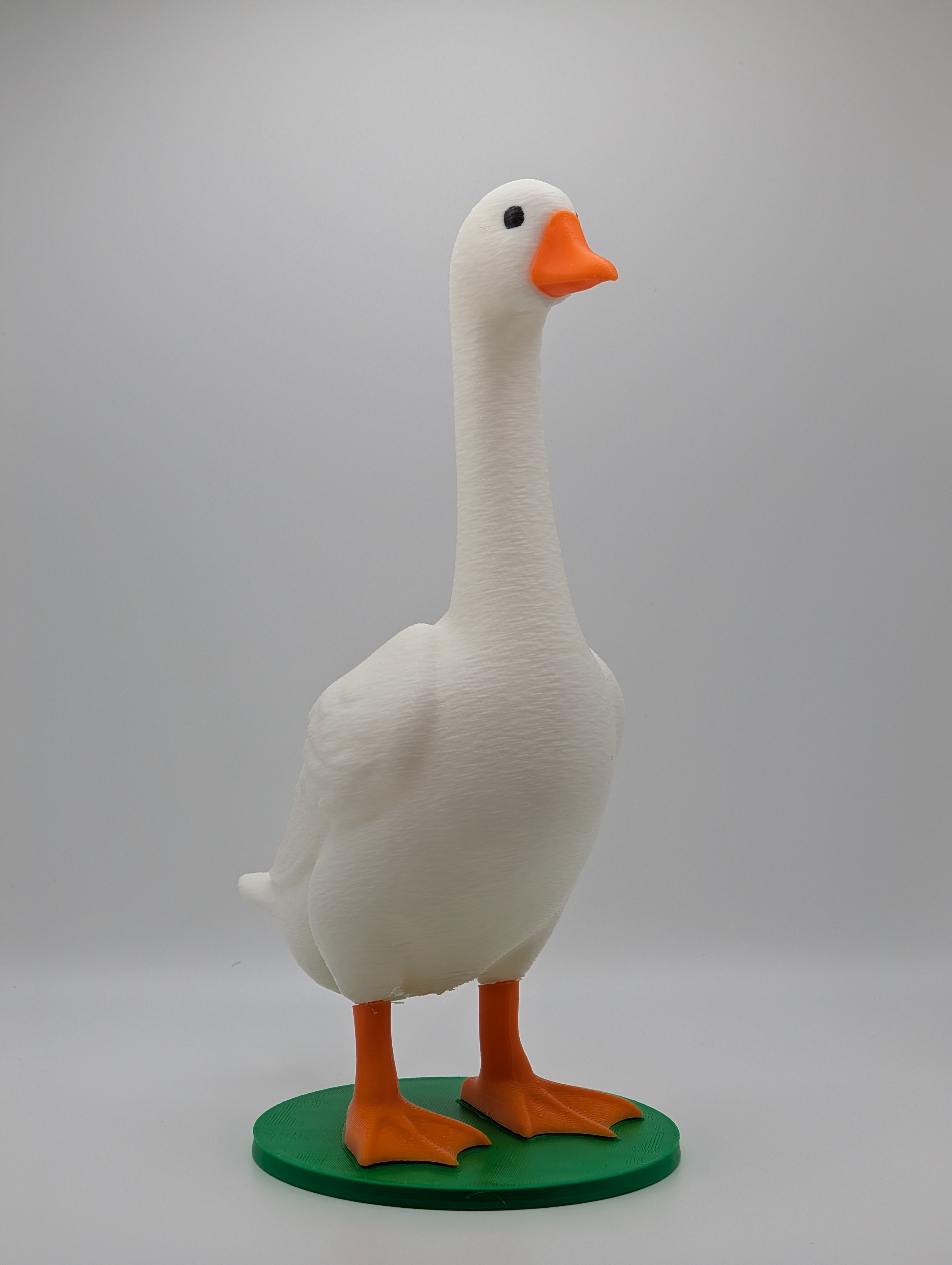 White 3D printed desk goose with an orange beak and feet on a green base